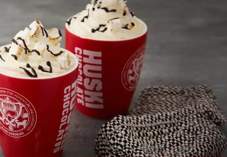 Twee rode Huski-mokken warme chocolademelk met slagroom en marshmallows